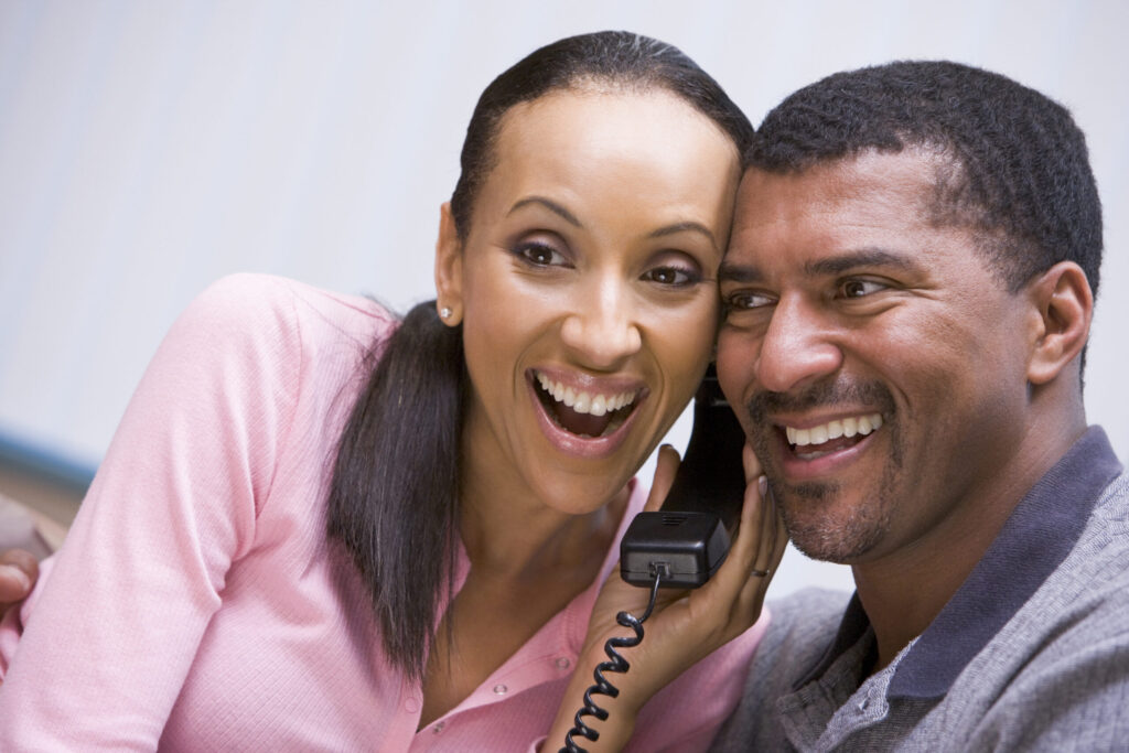 Couple receiving good news over phone at home